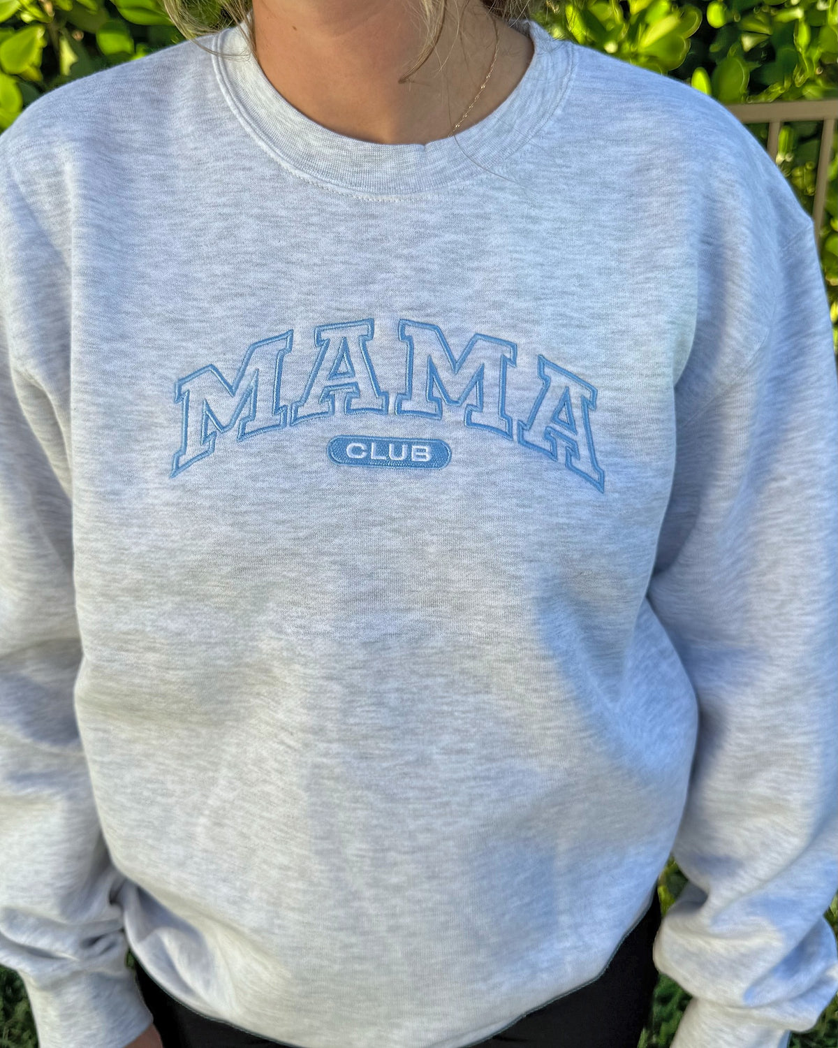 Close-up of the dusty blue outline MAMA CLUB embroidery on the heather grey crewneck
