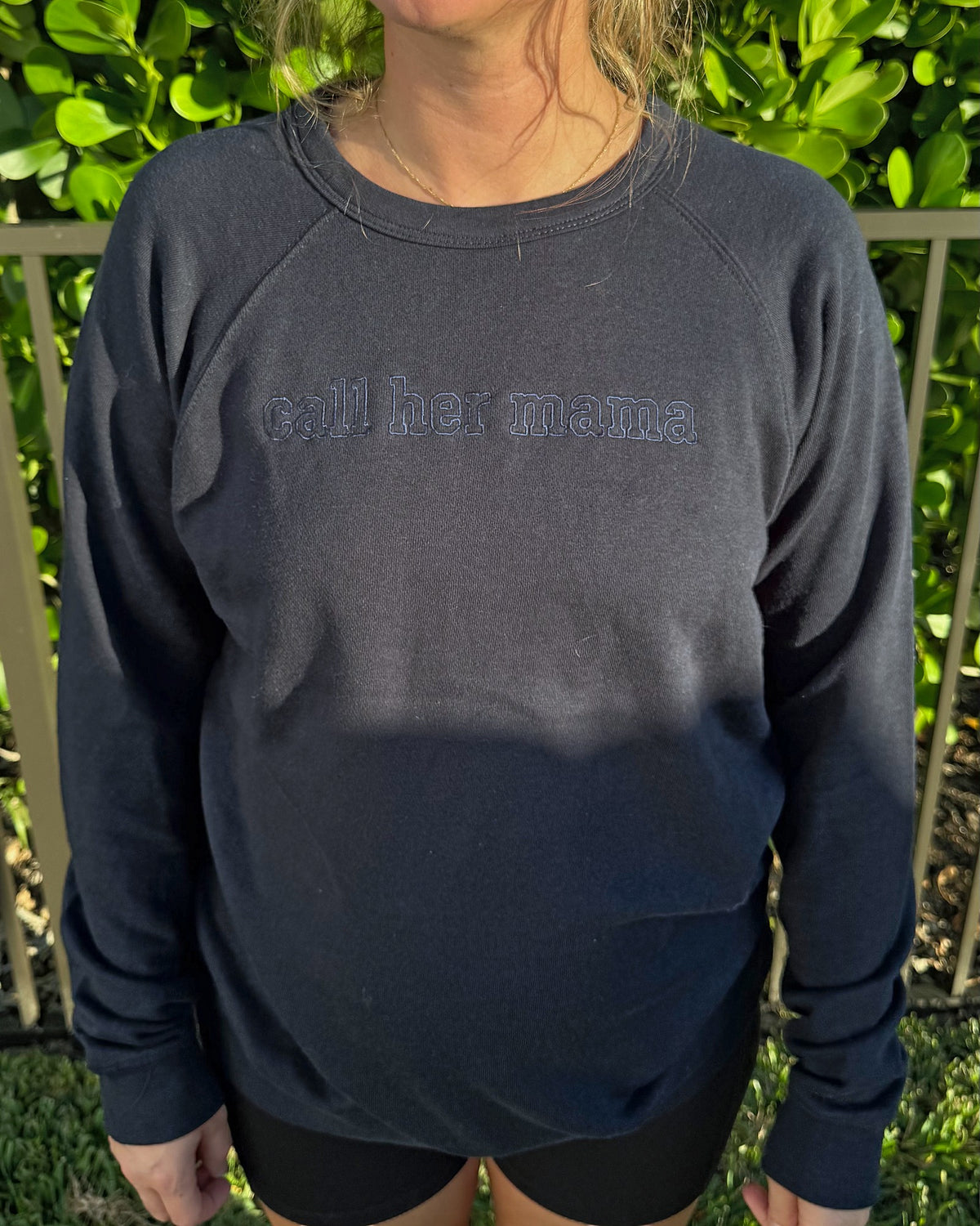 Close-up of the tone-on-tone outline call her mama embroidery on the navy crewneck