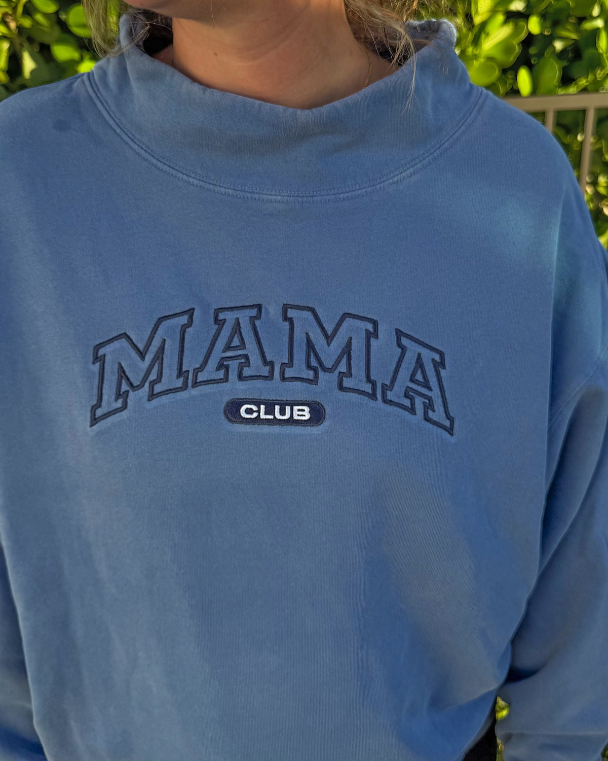 Close-up of the navy outline MAMA CLUB embroidery on the blue mock neck