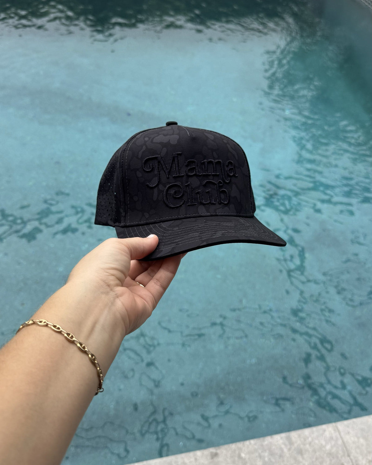 Mama Club black camo performance trucker held up by the pool