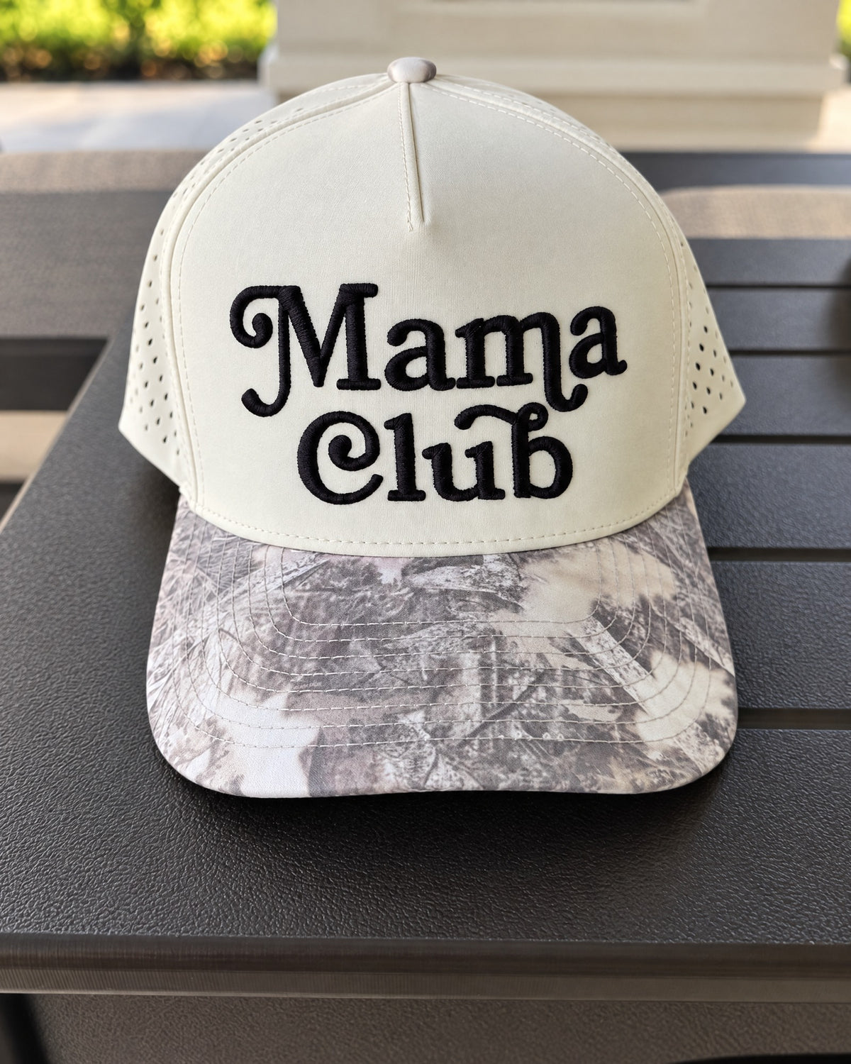 Mama Club white and grey camo trucker on a patio table