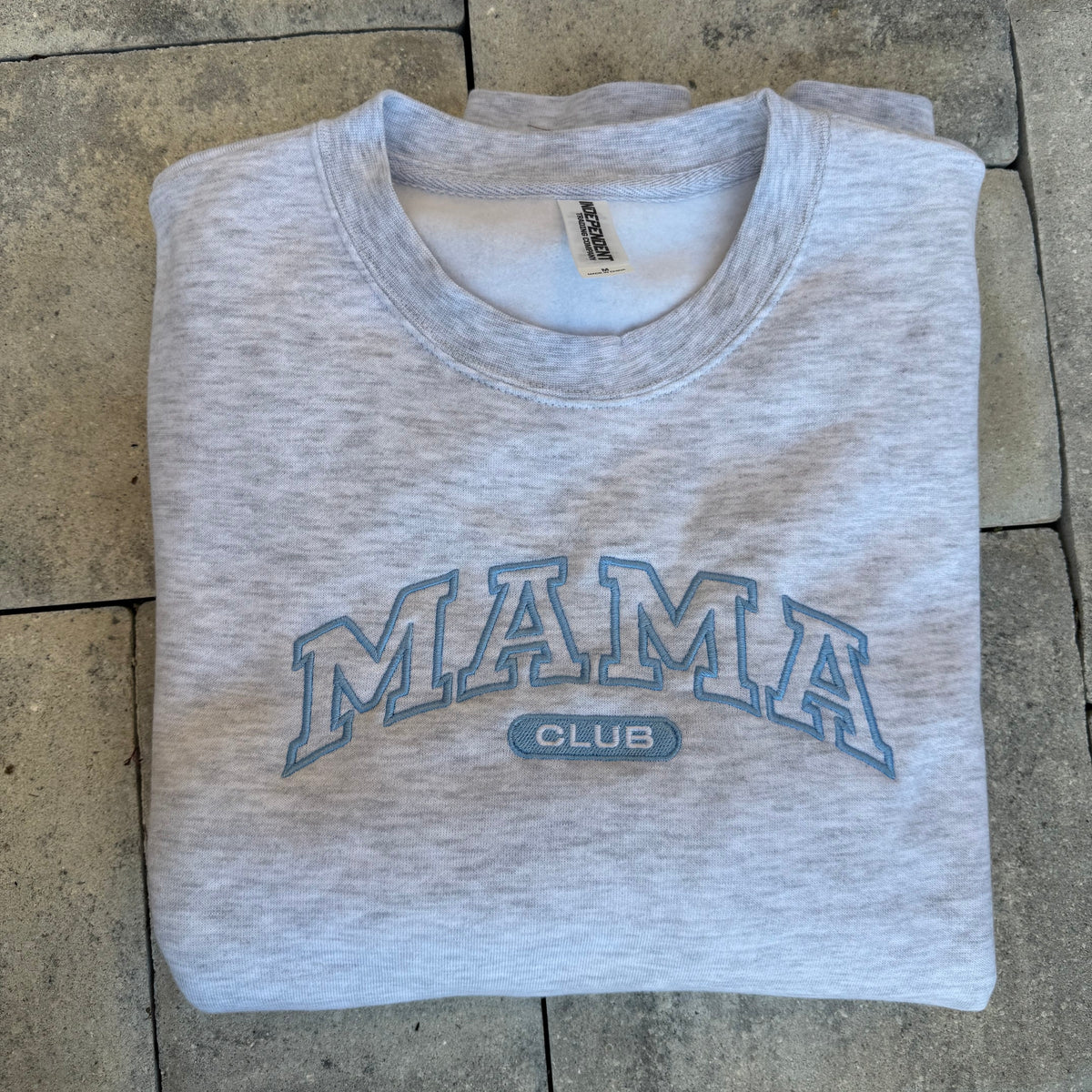 Grey Mama Club crewneck with blue embroidery, photographed flat on stone from the Call Her Mama photoshoot